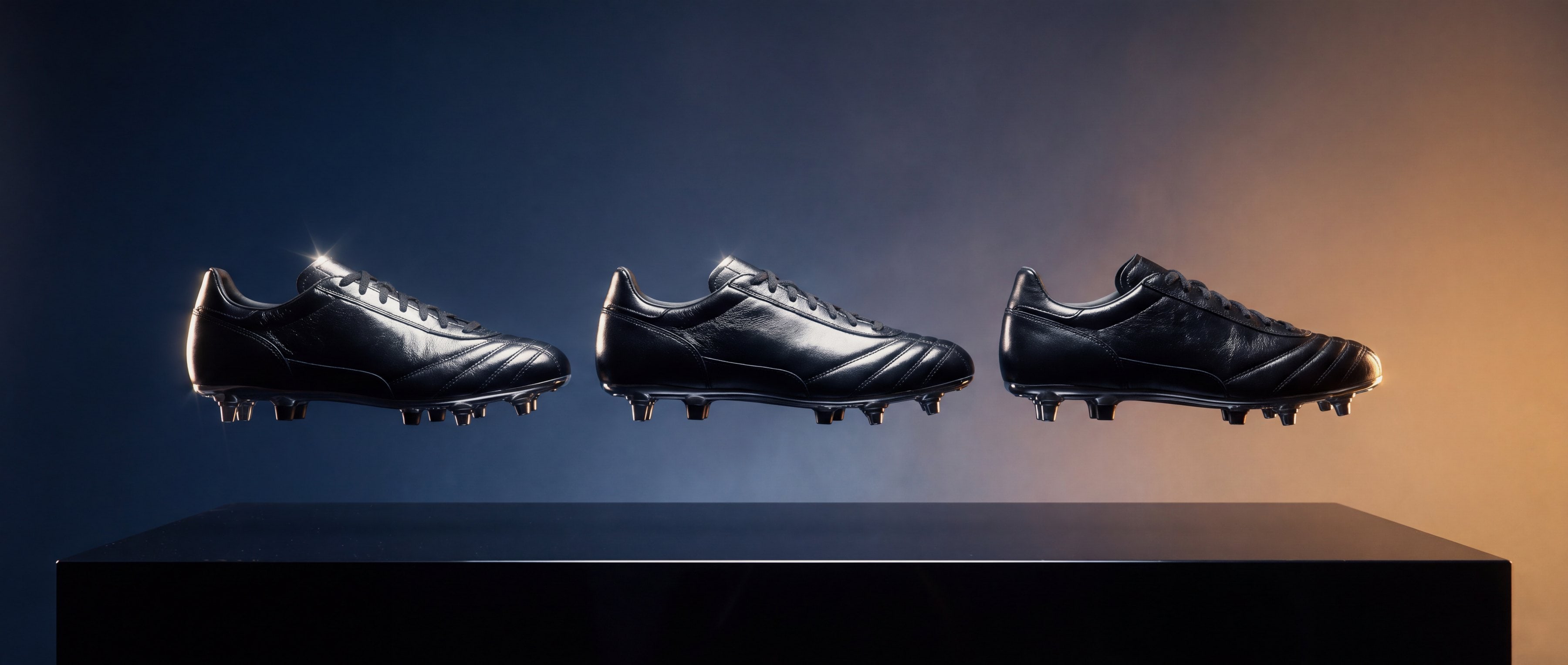 Three black leather football boots floating above a dark plinth