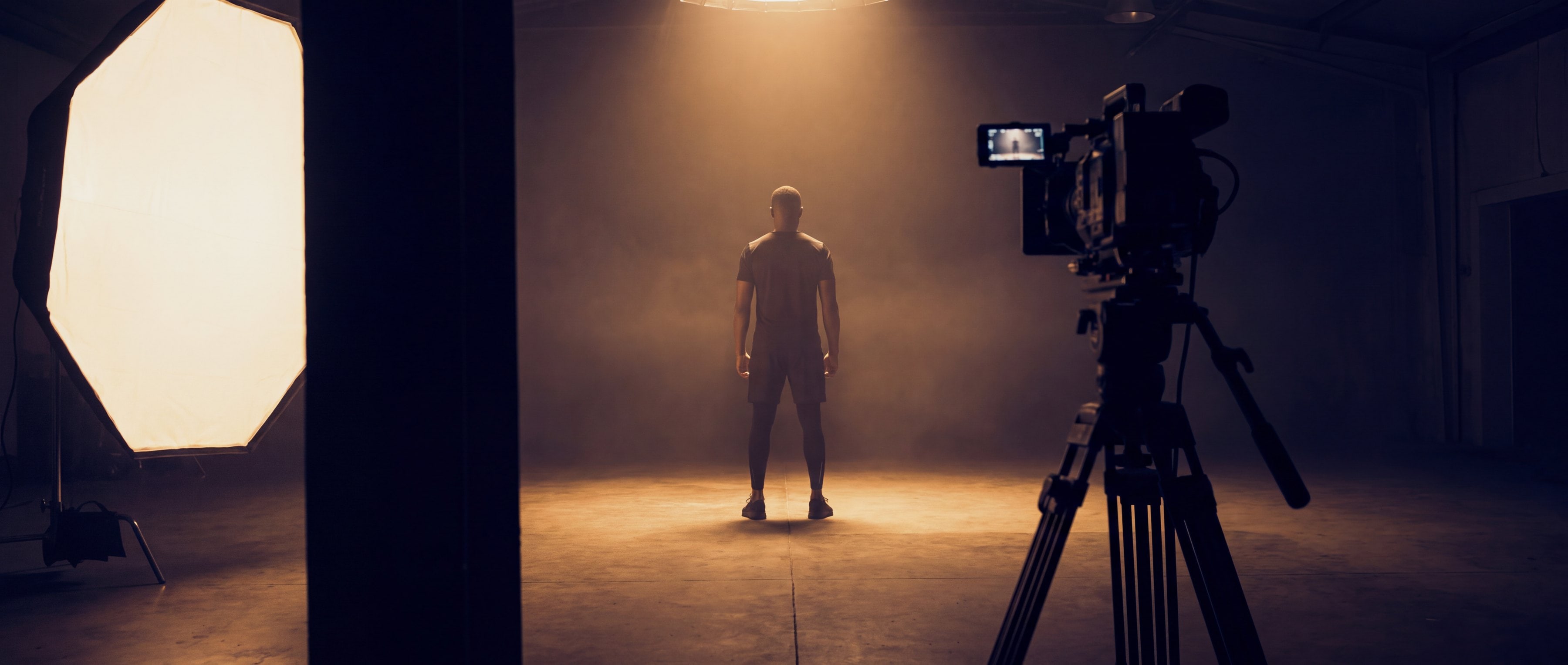 A campaign shoot in a studio: an athlete lit between a softbox and a camera